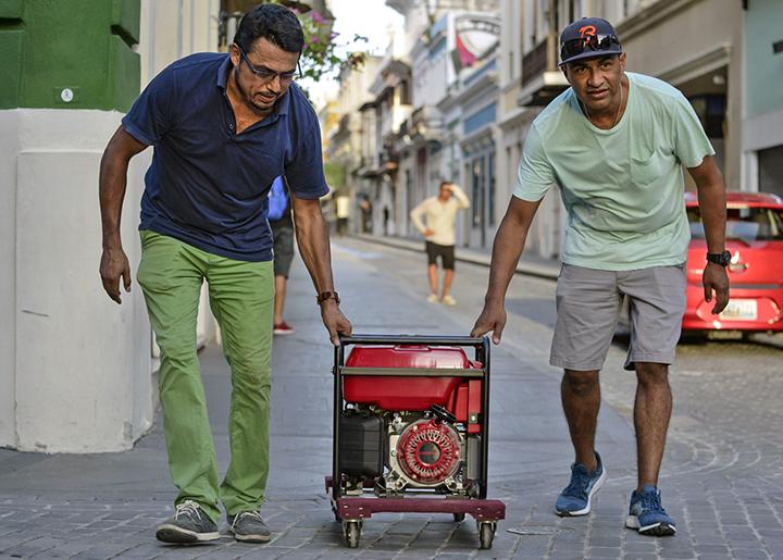 Residents roll a portable generator through the streets of San Juan