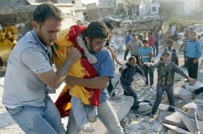 Aleppo residents carry a wounded child away from the site of government bombing