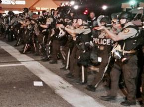 Police clad in riot gear move down West Florissant in Ferguson, Mo.