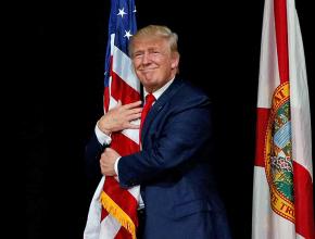 Donald Trump hugs the American flag before a speech in Tampa, Florida